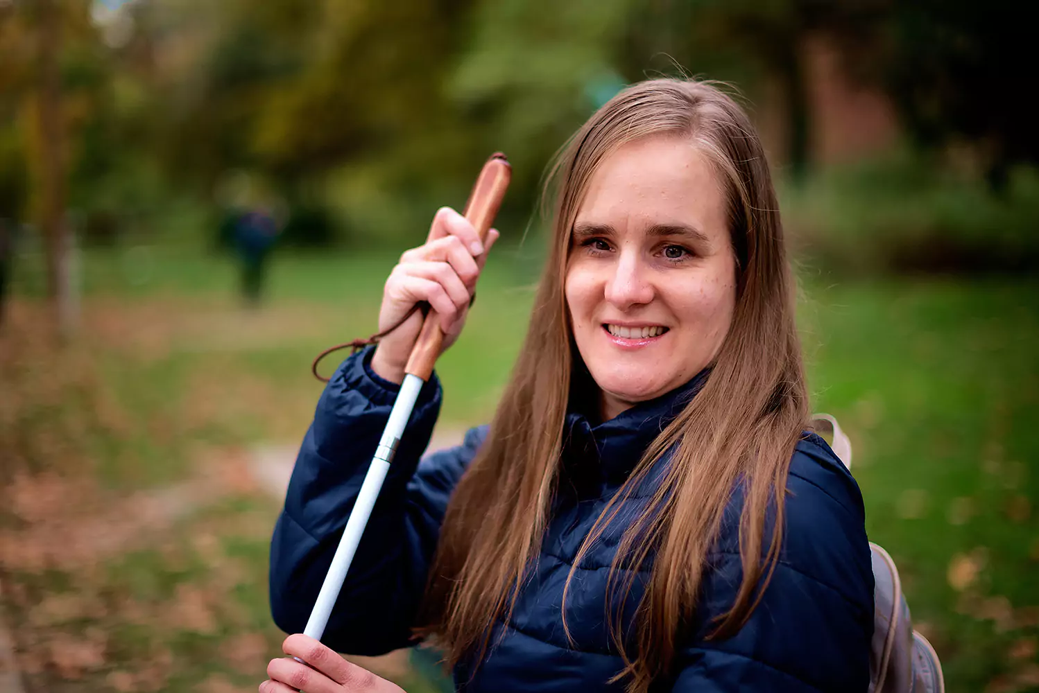 A blind woman is smiling while sitting in a park