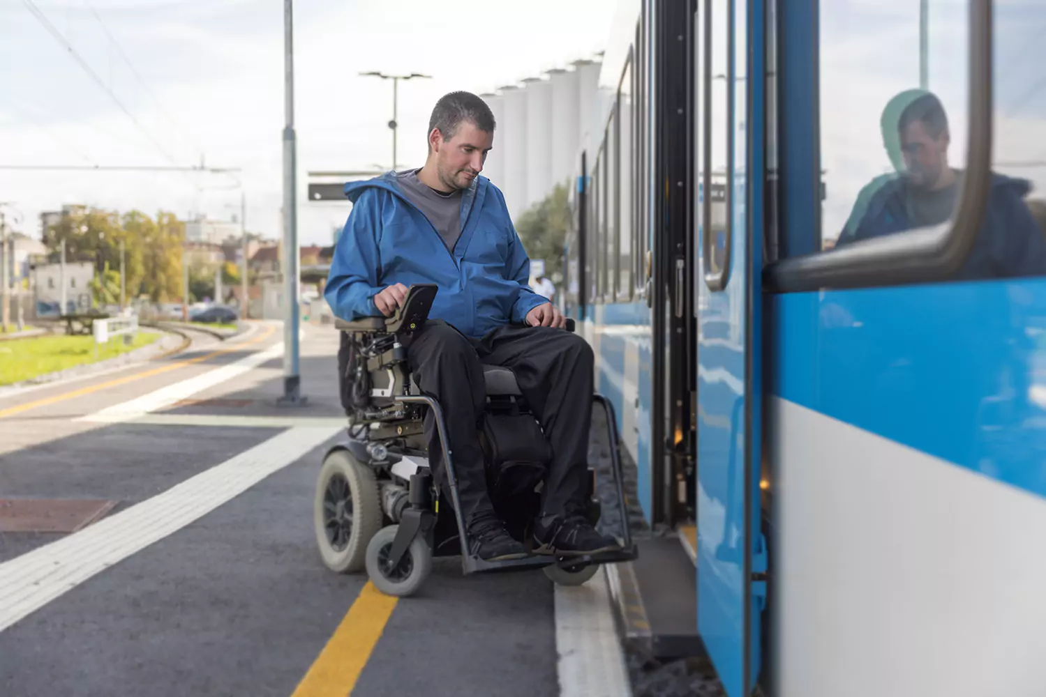 A physically disabled man is driving his electric wheelchair onto a public train