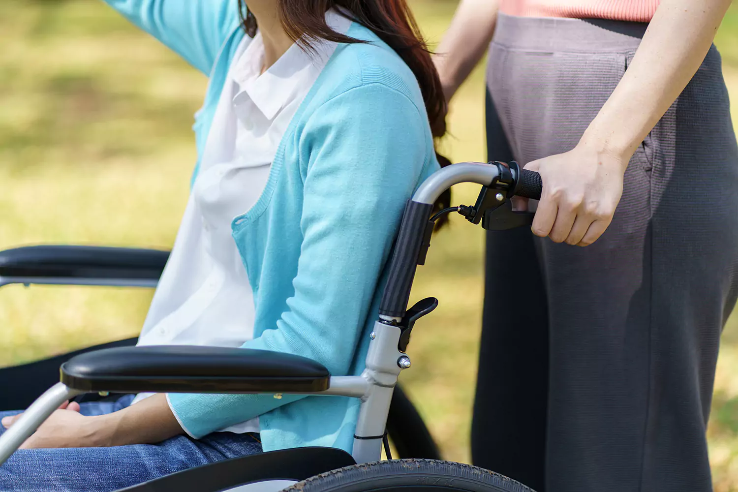 A young disabled woman is being pushed in a wheelchair by her support worker